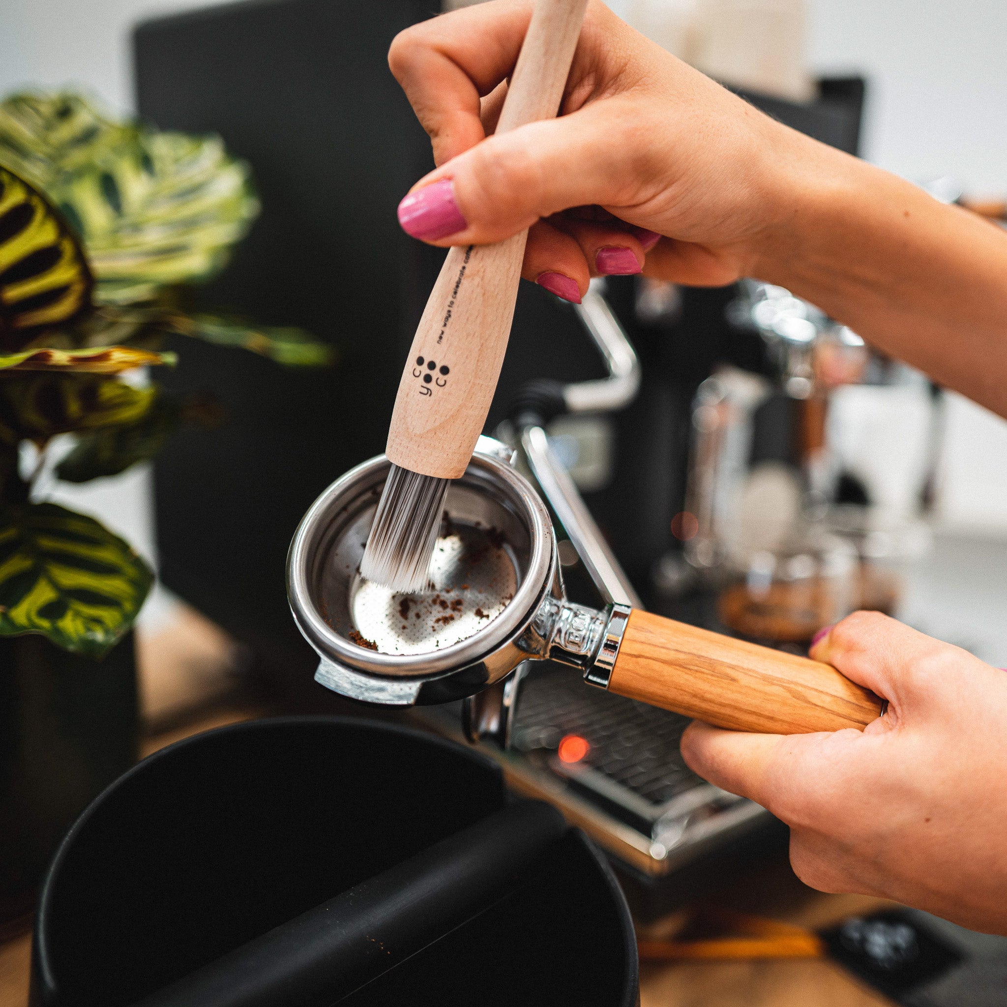 Altes Kaffeemehl wird aus dem Siebträger mit dem Barista-Pinsel entfernt.