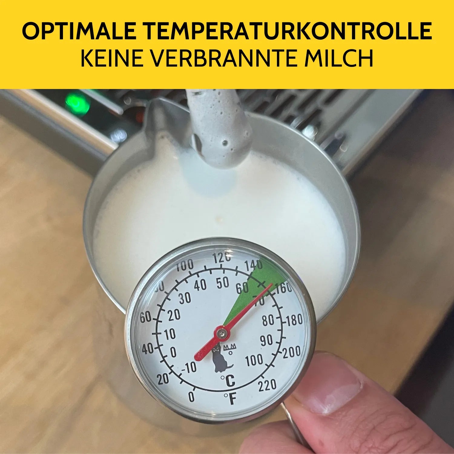 Milch wird aufgeschäumt und am Milchkännchen ist das Thermometer zur Kontrolle befestigt. 